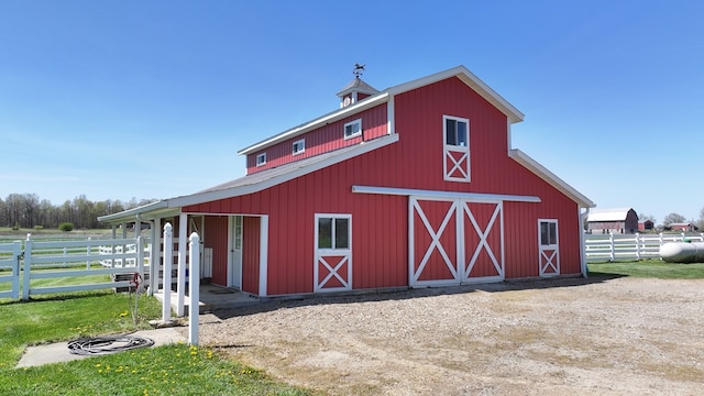 view of barn featuring fence and an exterior structure