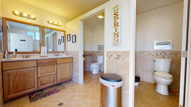 bathroom featuring a wainscoted wall, tile patterned floors, toilet, and tile walls