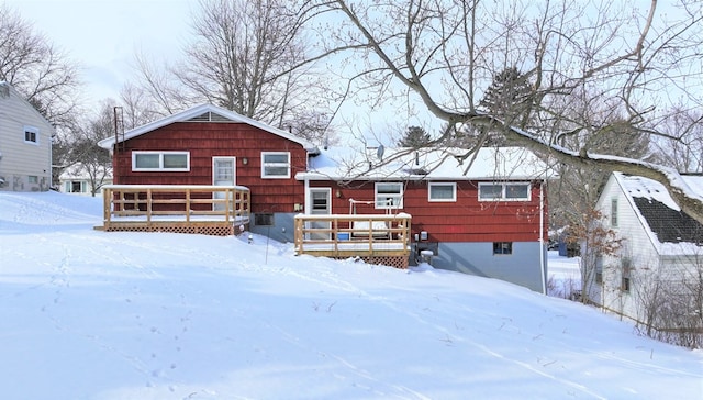 snow covered house featuring a wooden deck