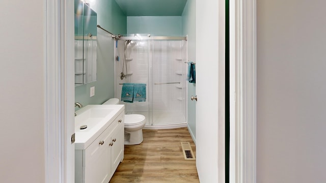 bathroom featuring visible vents, toilet, wood finished floors, a shower stall, and vanity