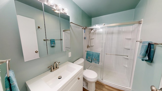 full bath featuring wood finished floors, toilet, a stall shower, and vanity