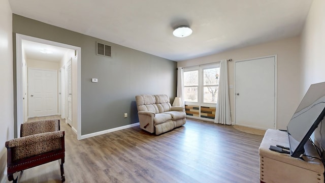 living area with wood finished floors, visible vents, and baseboards