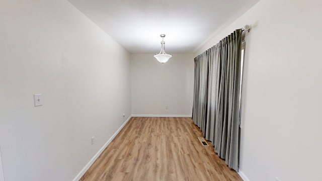 empty room with visible vents, light wood-style floors, and baseboards