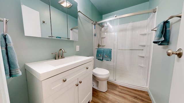 bathroom featuring a stall shower, toilet, vanity, and wood finished floors