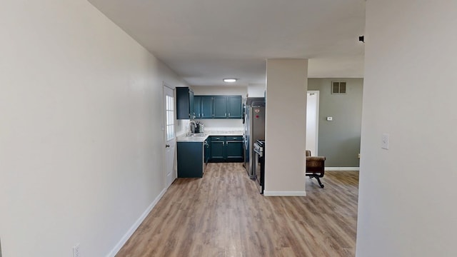 kitchen with light wood finished floors, visible vents, baseboards, light countertops, and freestanding refrigerator