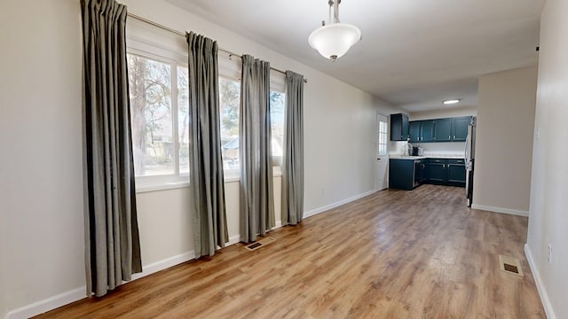 unfurnished dining area featuring visible vents, light wood-style flooring, and baseboards