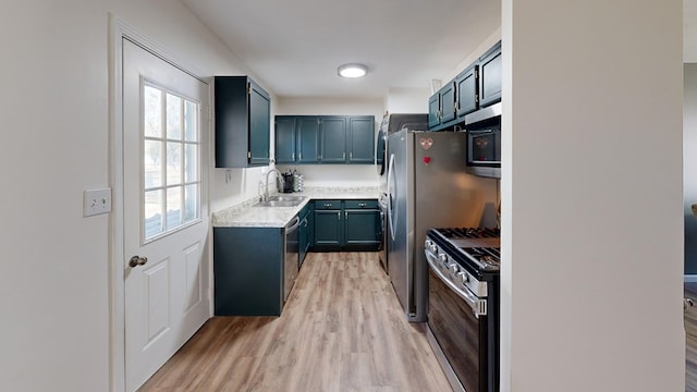 kitchen with a sink, stainless steel appliances, light wood-type flooring, and light countertops