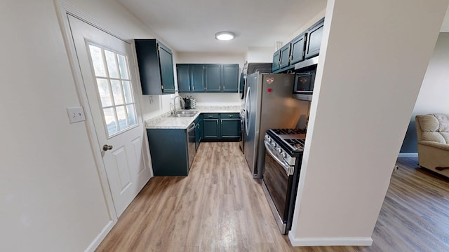 kitchen featuring appliances with stainless steel finishes, light wood-type flooring, light countertops, and a sink