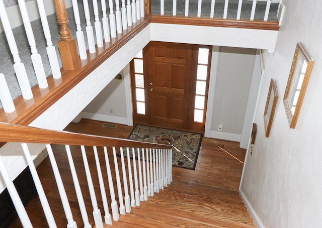 entryway featuring wood finished floors, visible vents, baseboards, and stairway