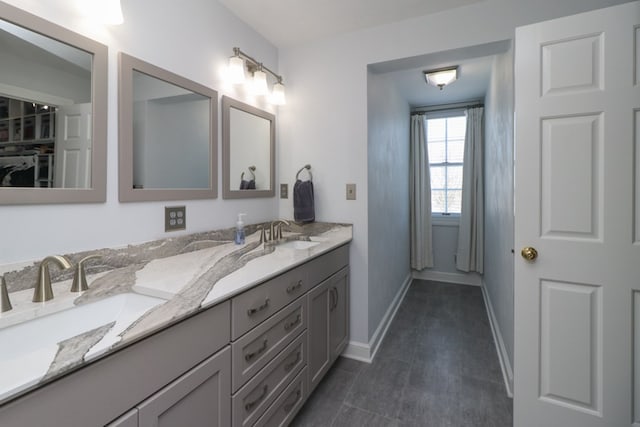 bathroom featuring a sink, baseboards, and double vanity