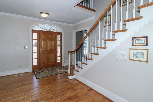 foyer entrance with stairway, wood finished floors, visible vents, crown molding, and baseboards