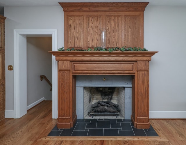 room details featuring baseboards, wood finished floors, and a tile fireplace