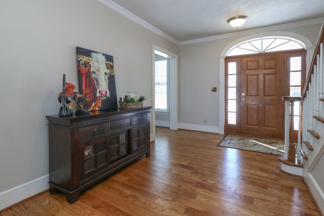 foyer entrance with baseboards, wood finished floors, stairs, and ornamental molding