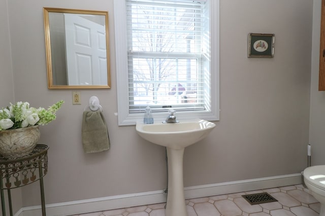 half bathroom featuring toilet, visible vents, and baseboards