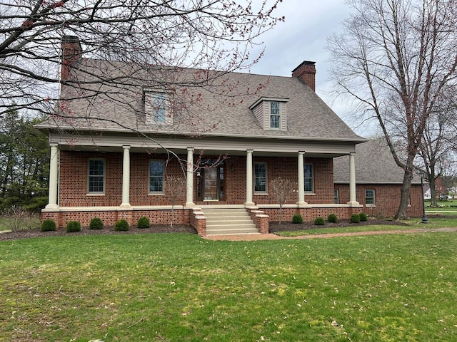 view of front facade featuring a chimney, a front yard, brick siding, a porch, and a shingled roof