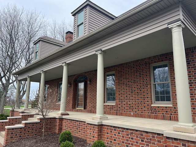 view of side of property with brick siding and covered porch