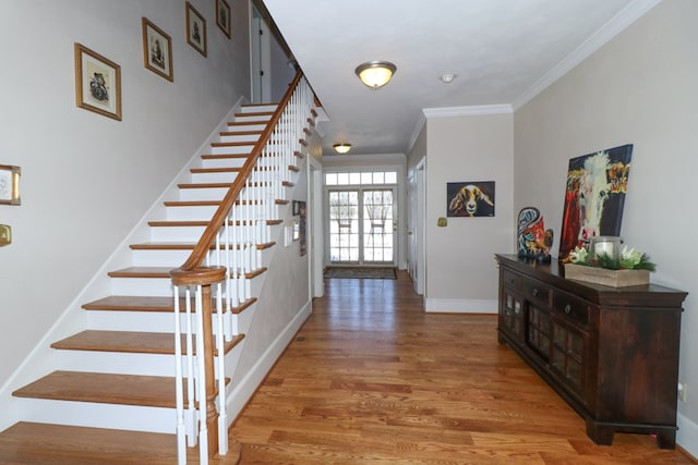 entryway featuring crown molding, wood finished floors, baseboards, and stairway
