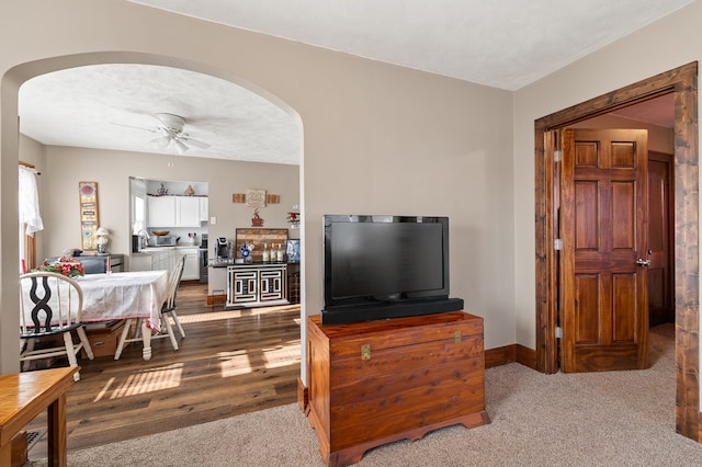 living room featuring a ceiling fan, arched walkways, a textured ceiling, and baseboards