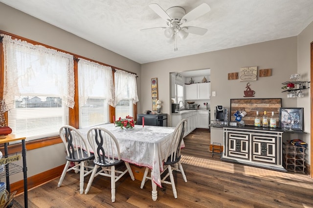 dining room featuring a textured ceiling, dark wood finished floors, a ceiling fan, and baseboards