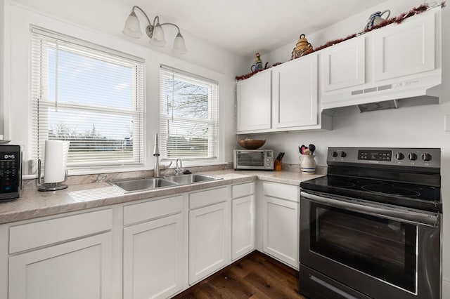 kitchen with light countertops, stainless steel electric range, a sink, and white cabinetry