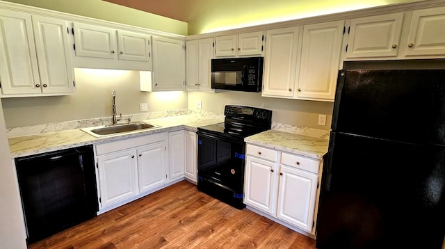 kitchen with black appliances, white cabinets, a sink, and light wood finished floors