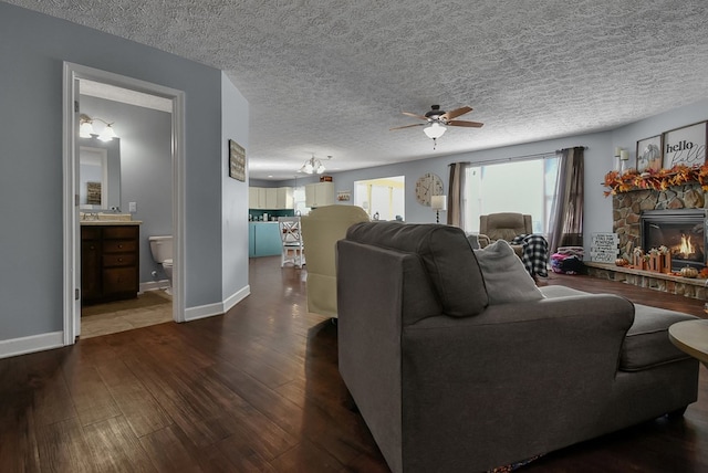 living room featuring a fireplace, a textured ceiling, dark hardwood / wood-style floors, and ceiling fan