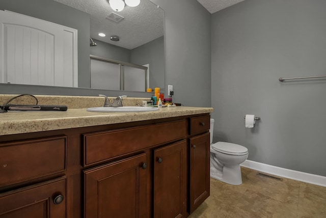 bathroom with vanity, a textured ceiling, toilet, and an enclosed shower