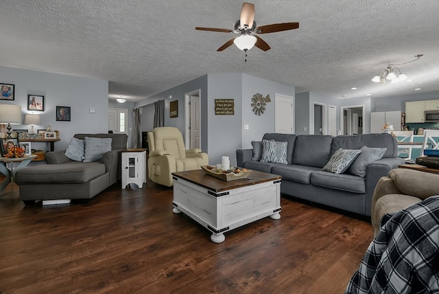 living room with a textured ceiling, ceiling fan with notable chandelier, and dark wood-type flooring