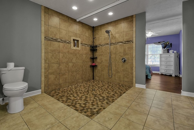 bathroom featuring ceiling fan, tile patterned floors, a textured ceiling, tiled shower, and toilet