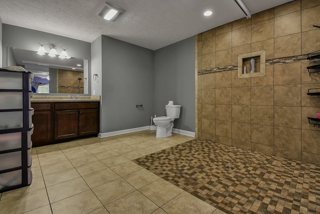 bathroom featuring a tile shower, tile patterned floors, a textured ceiling, toilet, and vanity