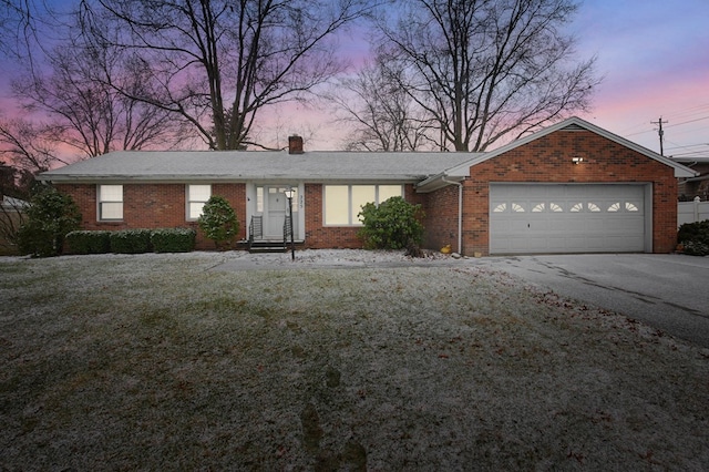 ranch-style home with a garage and a lawn