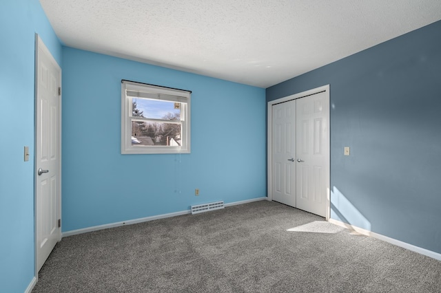 unfurnished bedroom featuring visible vents, carpet flooring, a textured ceiling, and baseboards