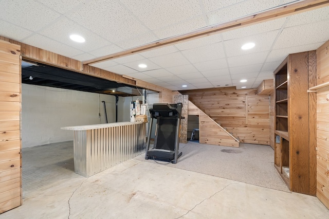 finished below grade area featuring concrete block wall, recessed lighting, wood walls, and a paneled ceiling