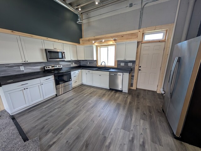 115 N Main St, Mount Gilead, OH 43338 - kitchen featuring a sink, backsplash, a high ceiling, appliances with stainless steel finishes, and dark countertops