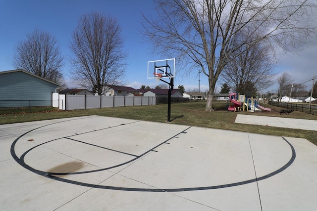 view of basketball court featuring fence, basketball court, a playground, and a yard