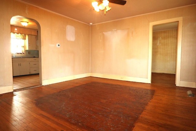 empty room featuring ornamental molding, arched walkways, hardwood / wood-style floors, and a ceiling fan