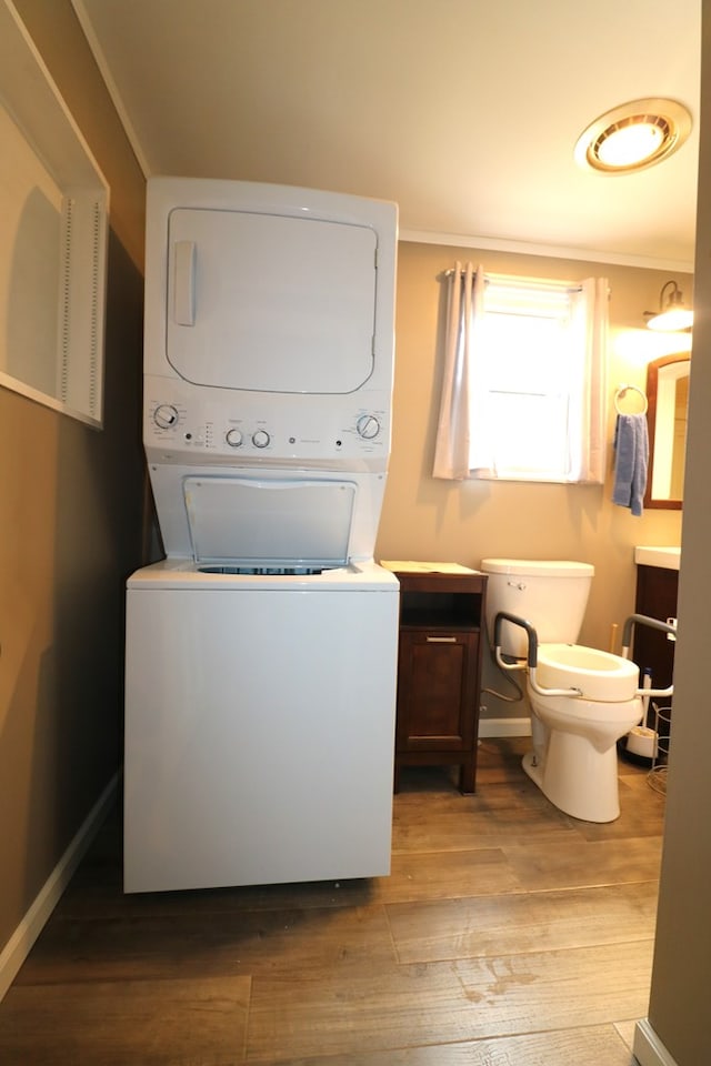 washroom with laundry area, light wood finished floors, stacked washing maching and dryer, and baseboards