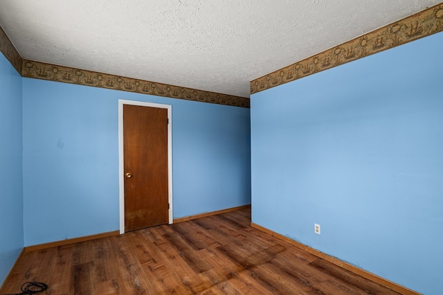 empty room with dark hardwood / wood-style floors and a textured ceiling