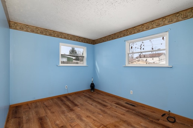 spare room with dark hardwood / wood-style floors and a textured ceiling