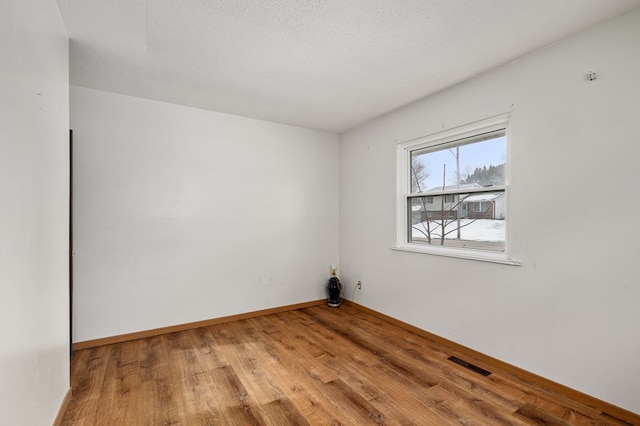 unfurnished room with hardwood / wood-style floors and a textured ceiling