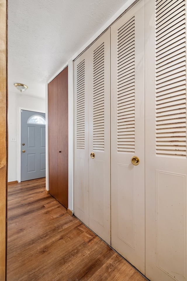 corridor with wood-type flooring and a textured ceiling