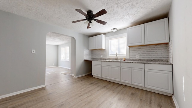 kitchen with white cabinetry, decorative backsplash, and light hardwood / wood-style floors