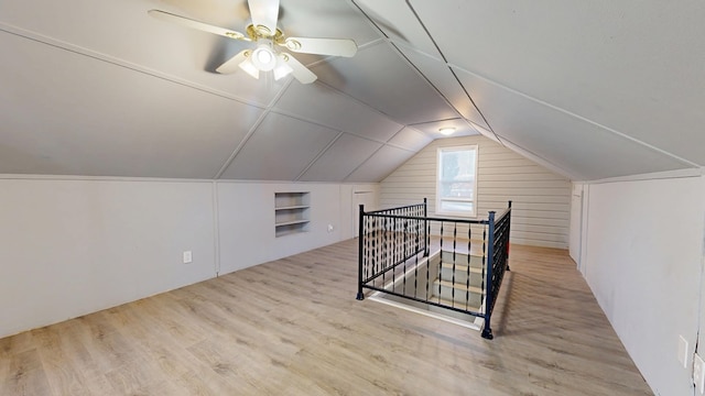 additional living space featuring built in shelves, ceiling fan, lofted ceiling, and light wood-type flooring