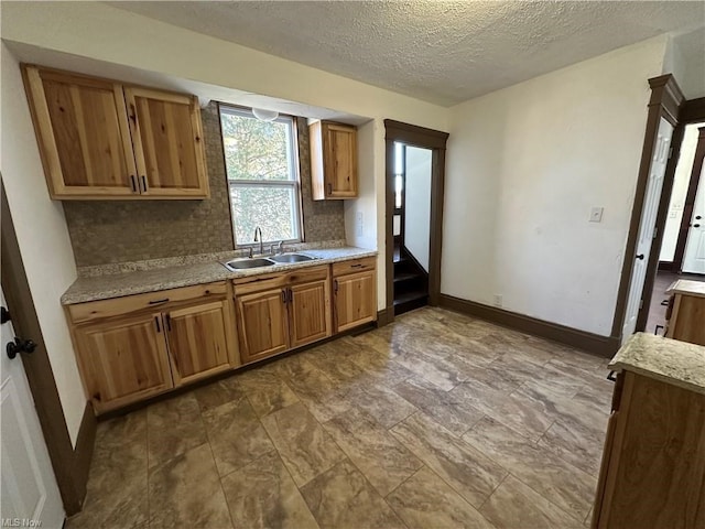 85 Penn Ave, Mansfield, OH 44903 - kitchen featuring a sink, brown cabinetry, tasteful backsplash, baseboards, and a textured ceiling