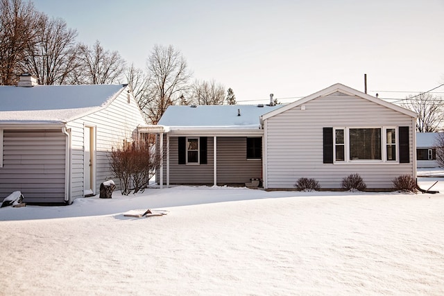 snow covered back of property with a garage