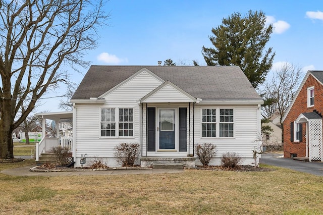 view of front of property with covered porch, driveway, a shingled roof, and a front yard