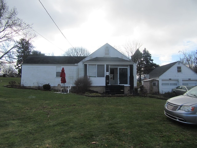 bungalow with an outbuilding, a garage, and a front lawn