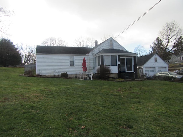 view of front facade featuring a sunroom, an outbuilding, a front lawn, and a garage