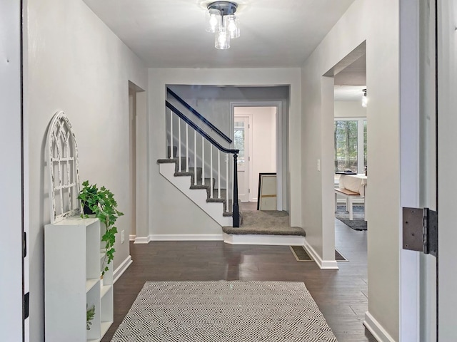 foyer featuring dark wood finished floors, stairway, and baseboards