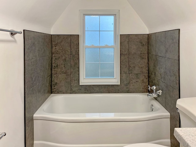 full bathroom with a bathing tub, toilet, and lofted ceiling